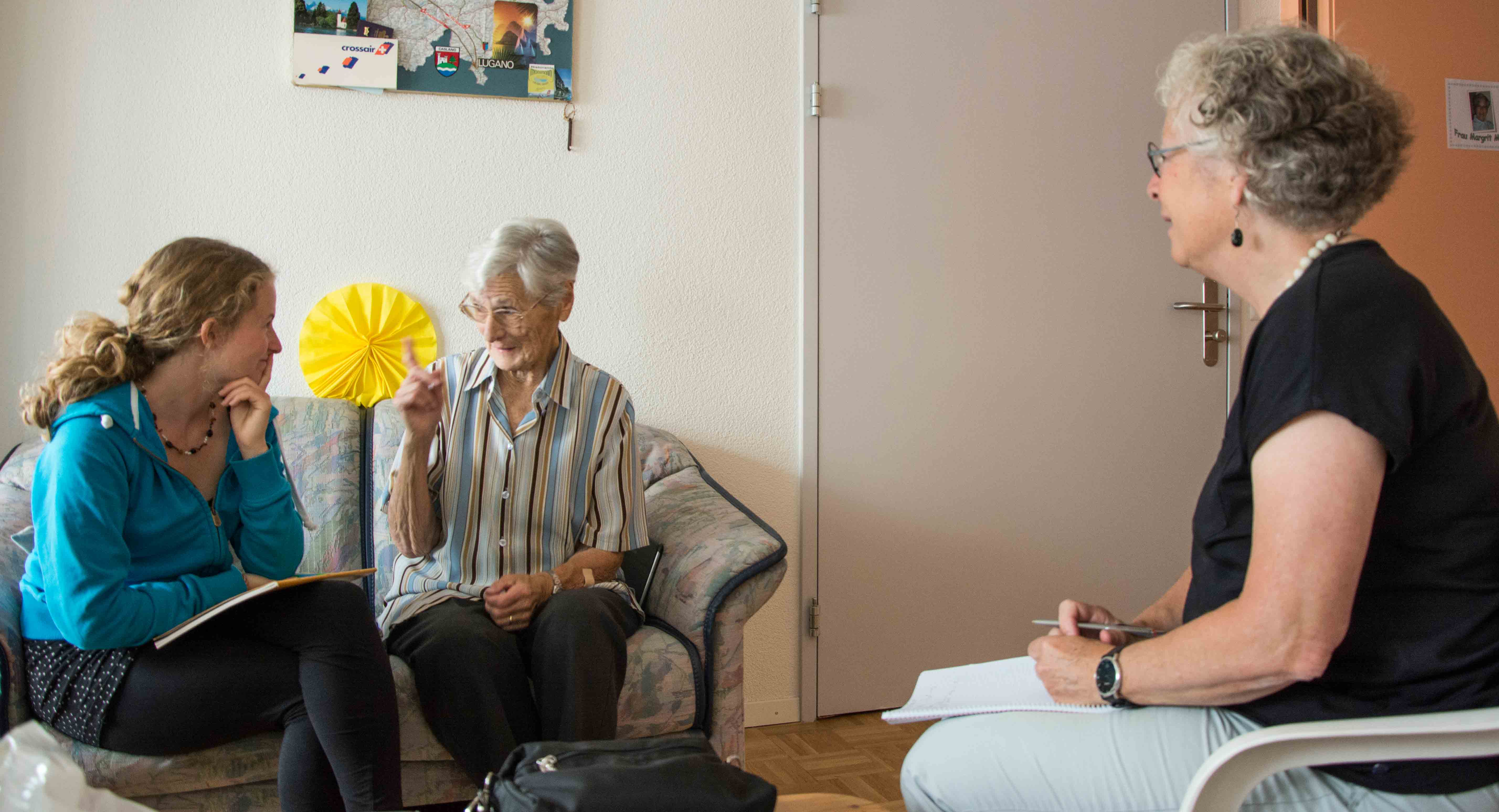 Besuch bei einer alten Dame: Die UND - Redaktorinnen Livia Thurian und Gaby Jordi hören gebannt zu. - Bild: Demian Thurian